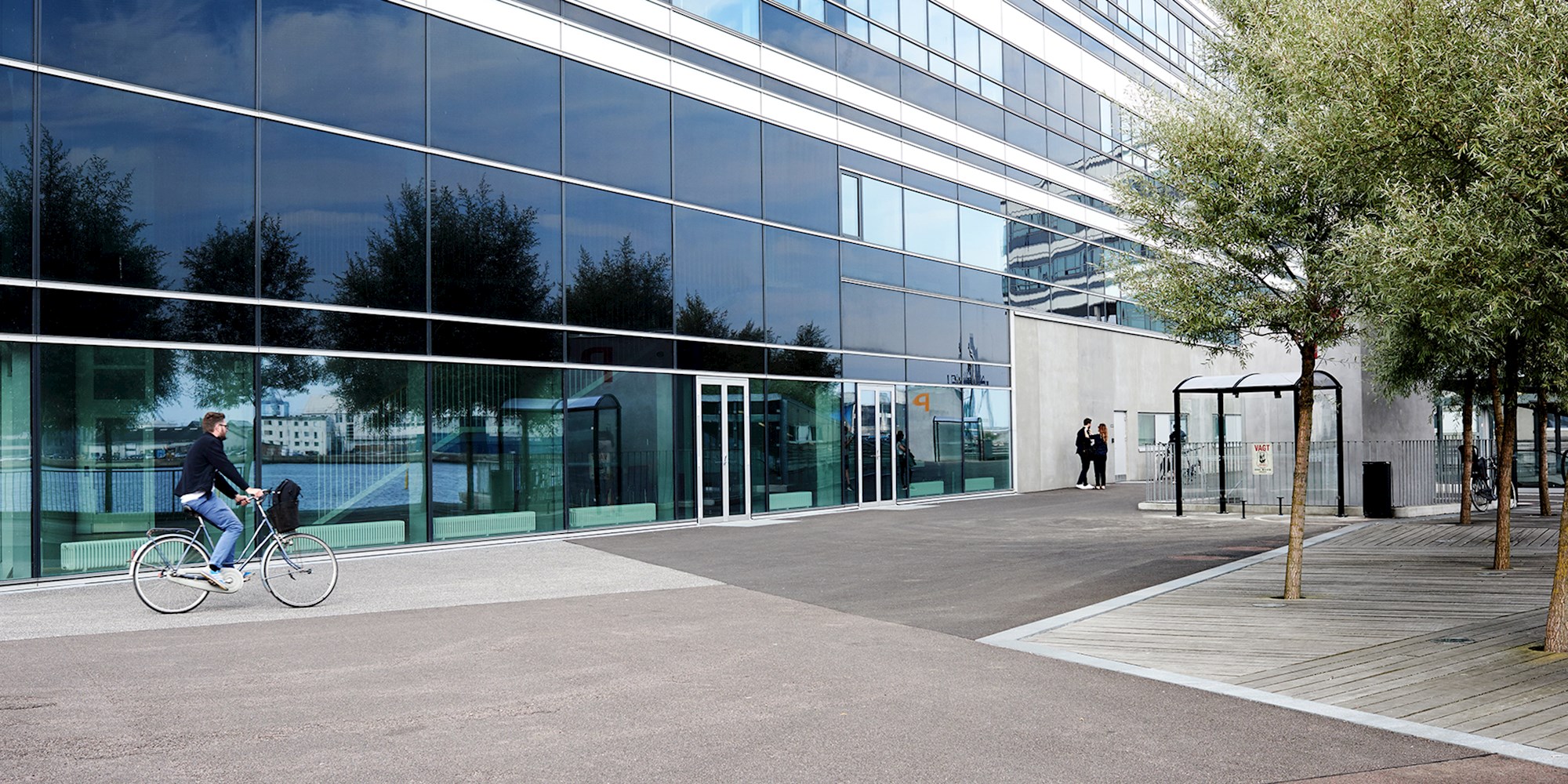 Man cycling in front a glass building